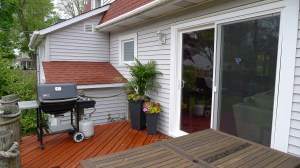 Weber propane grill, patio table and benches, and flowers on backyard deck